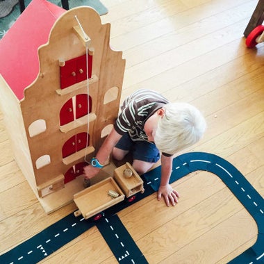 Child playing with wooden dollhouse.